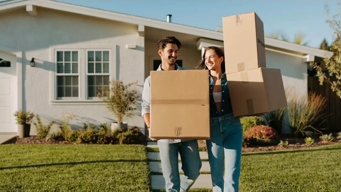 First-time buyers carrying moving boxes into their new home